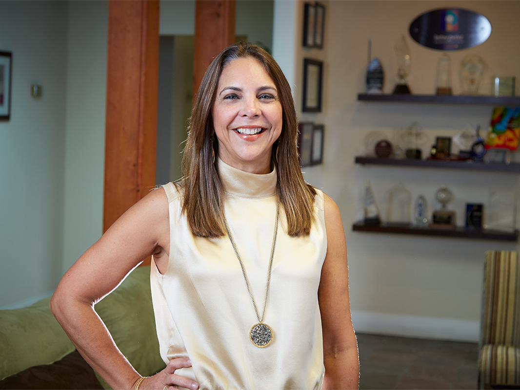 A woman standing in an office with trophies in the background