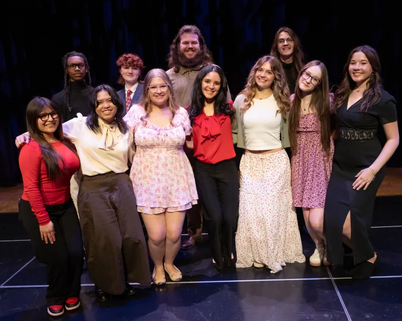 group of high school students posing together on a stage