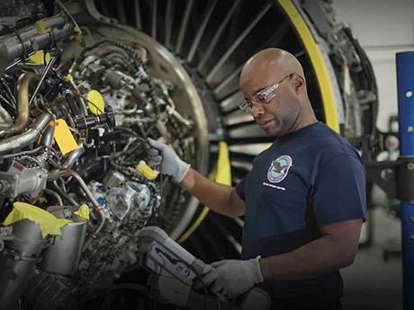 Maintaining Success A worker wearing gloves and safety goggles examines an airplane turbine at a facility in Georgia.