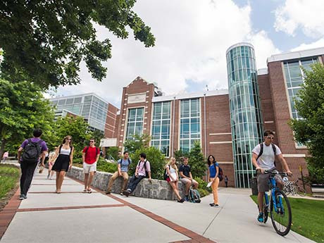 students ride bikes a walk on path at a university
