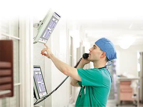 Digital Health IT nurse on the phone checks a monitor on the wall