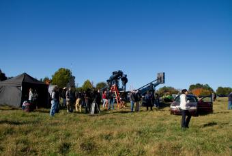 Large crew on set outside in a field in Georgia with multiple film production objects