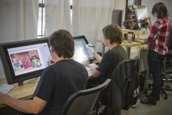 Two men indoors at a desk utilizing technology to create graphics 