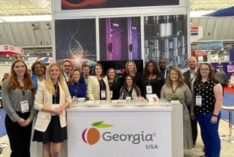 People gather at a life sciences event by a Georgia booth