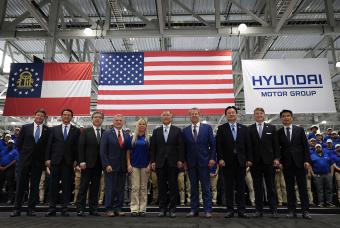 hyundai motor group standing in line together in front of flags