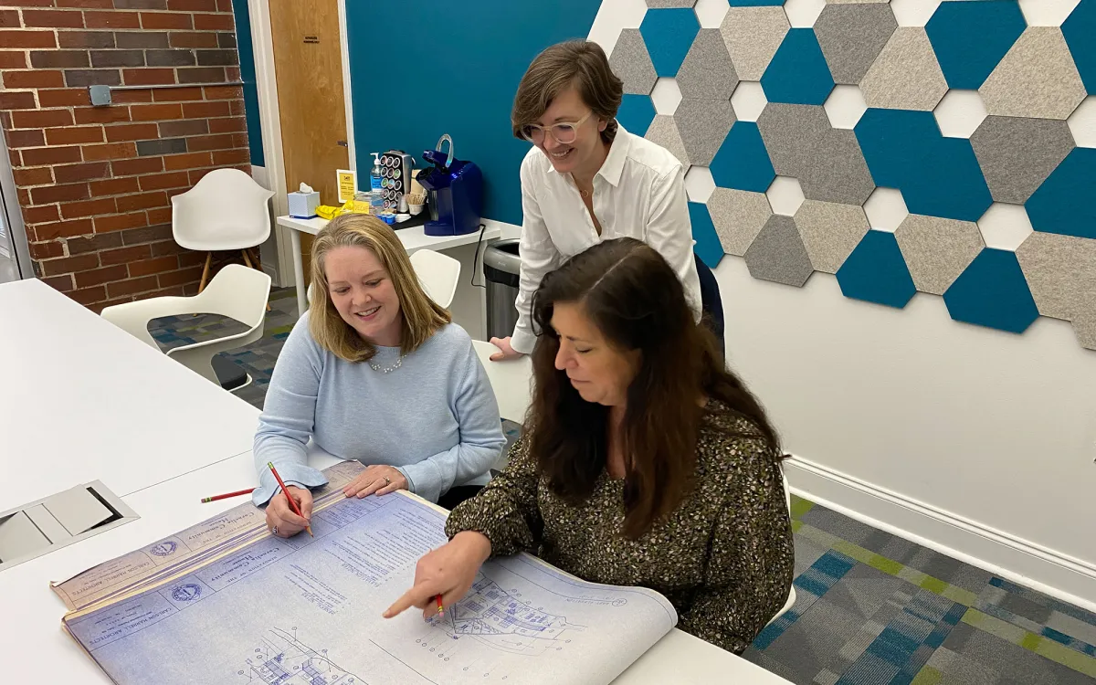 Three women look at blueprints at Shear Structural
