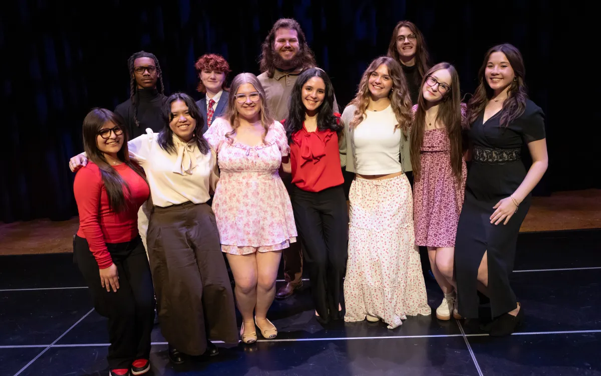 group of high school students posing together on a stage