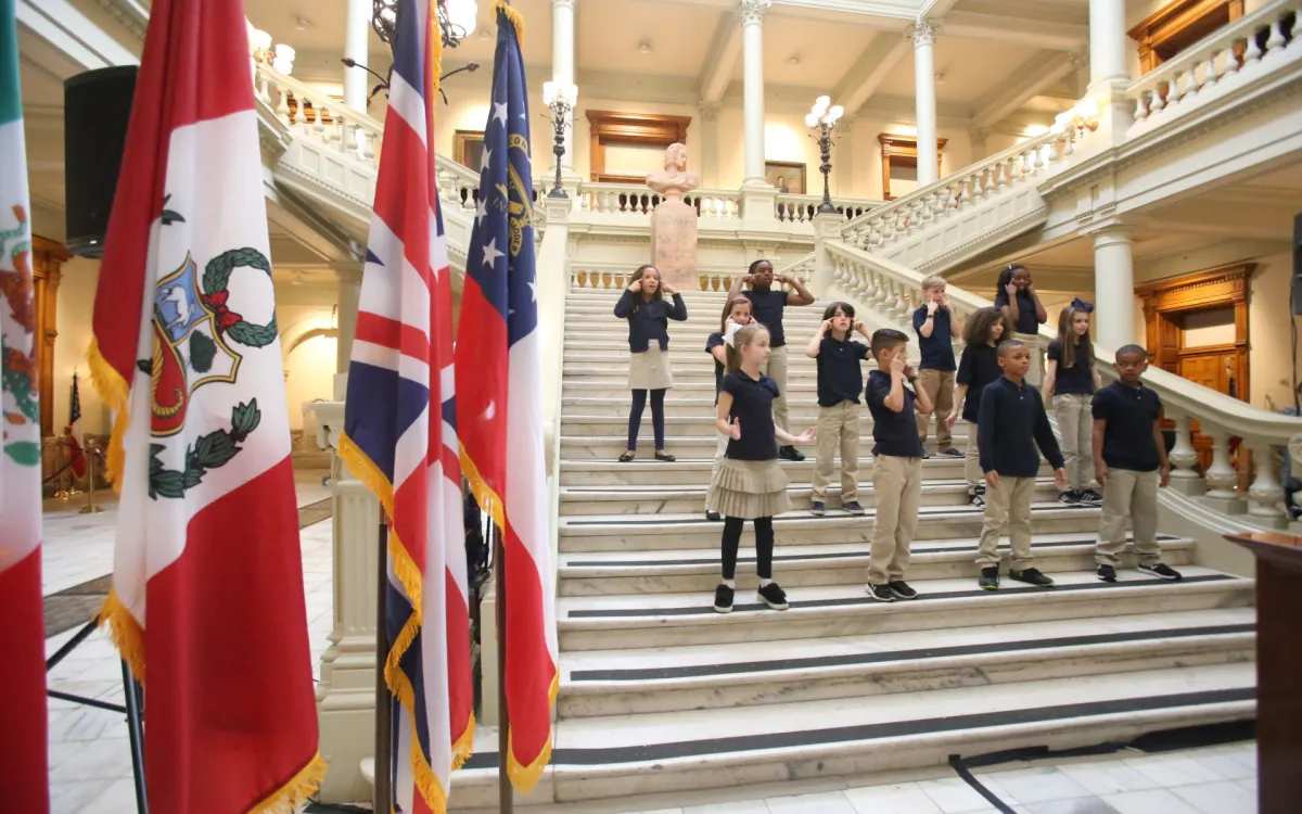Children perform on steps at the Georgia State Capitol with international flags nearby