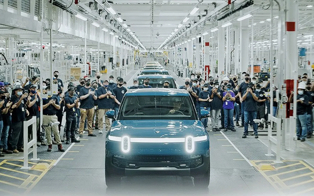 A Rivian car with staff surrounding it.