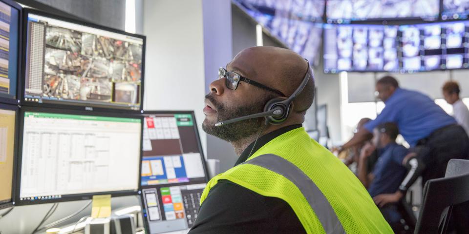 A worker monitors screens inside a control room.