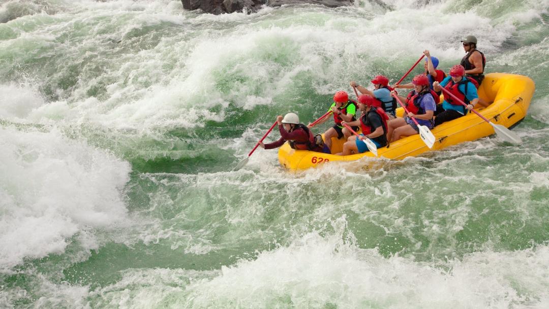 A group of people in a yellow raft go through whitewater on a river in Southwest Central Georgia