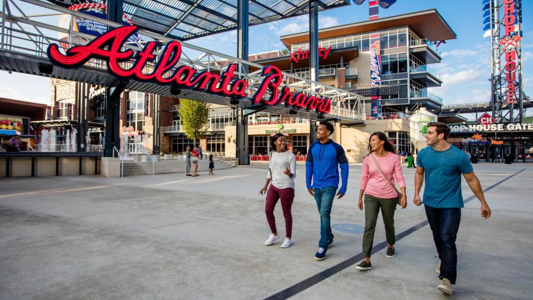 four young people walking in front of the Atlanta Braves stadium sign in Metro Atlanta