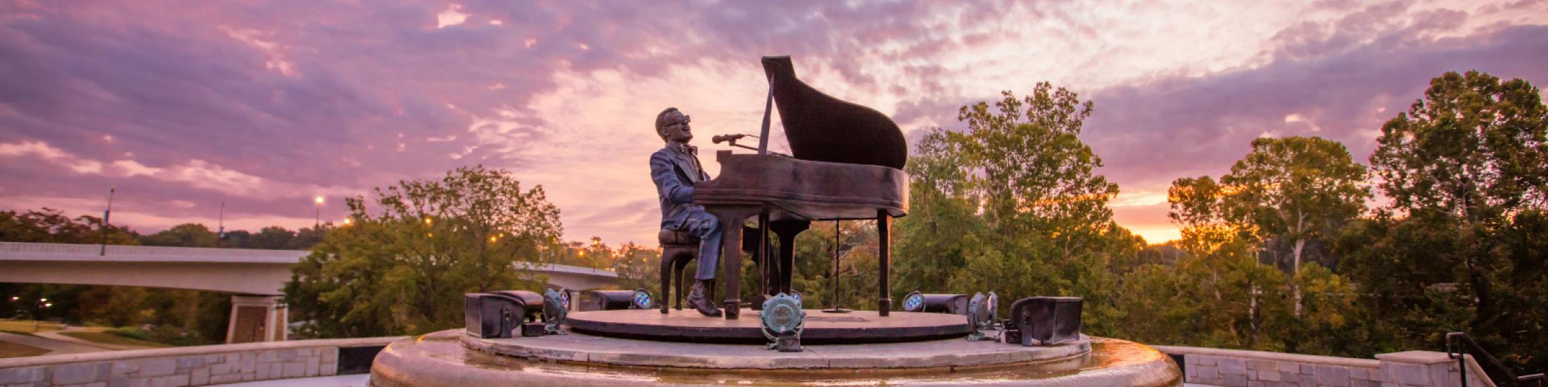 Statue of Ray Charles singing at a piano at sunset in Georgia