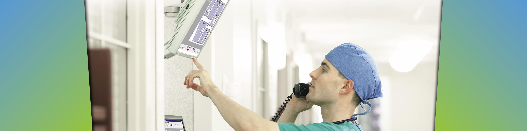 Nurse talks on phone while looking at and touching a screen on the wall
