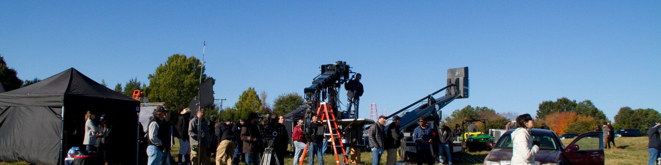 Large crew on set outside in a field in Georgia with multiple film production objects