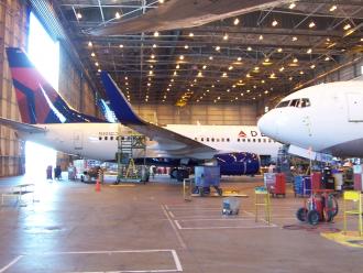 Large airplanes sit inside an airport hangar.