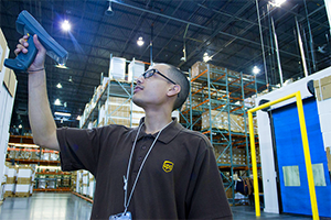 A UPS worker scans a stack of boxes