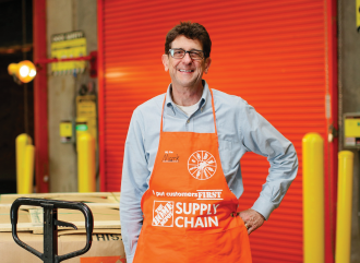 A person in a Home Depot orange apron smiles with their hand on their hip.