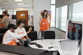 people in home depot aprons look at a tv screen, one person is wearing a virtual reality headset