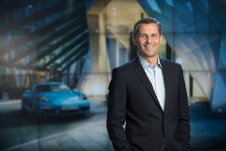 Leaders at Porsche poses in front of car in a suit in Metro Atlanta