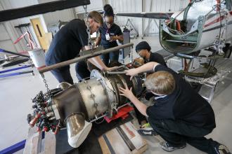 College students working on an airplane motor.