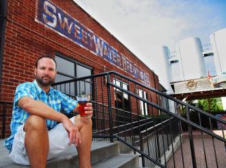 Sweetwater Brewing exterior with owner sitting on step in Metro Atlanta