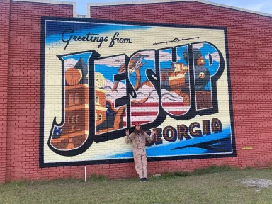 A painting on a brick wall displaying "Greetings from JESUP Georgia"