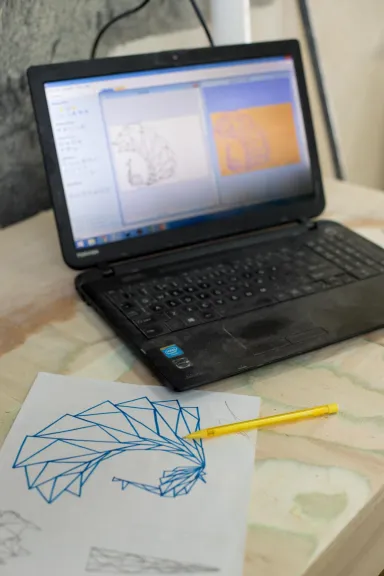 A laptop with product designs on screen next to a hand-drawn design
