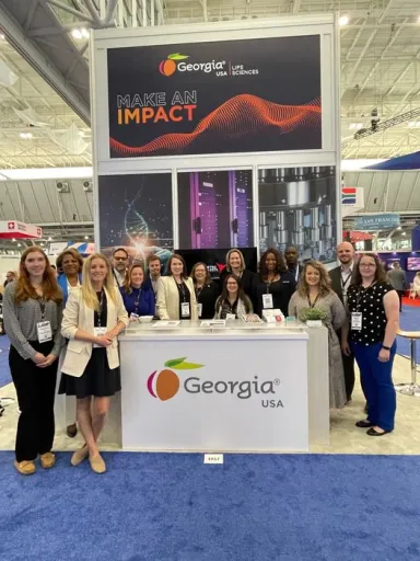 People gather at a life sciences event by a Georgia booth