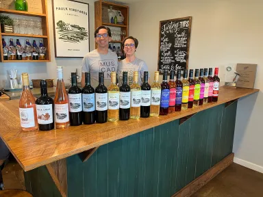 Chris and Jorjanne Paulk stand behind a bar with a display of wines in front.