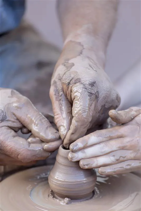Hands molding clay on a potter's wheel